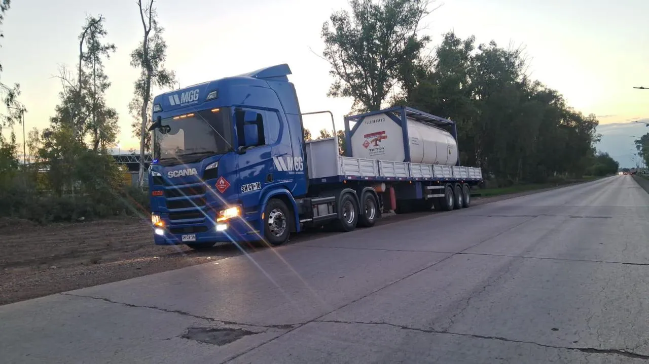 Camión azul con tanque contenedor en ruta al atardecer
